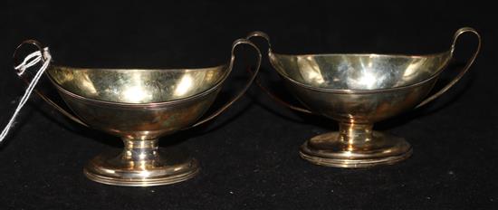 A pair of George III silver navette-shaped salts, with gilt interiors, upswept handles and reeded borders, London 1792, Moses Brent.